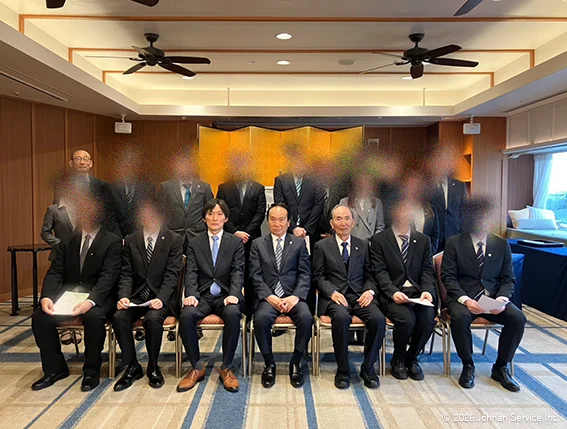 役員と社員が前後2列に並び、会場内で撮影した集合写真。