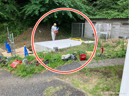 ガバナー本体設置用のコンクリート基礎が赤い円で強調された屋外の風景。作業服を着た人物が基礎のすぐ横に立っており、背景にはフェンスで囲まれた建物と緑地が見える。